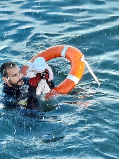 Un submarinista de la Guardia Civil, con un bebé cuya familia se había echado al agua en Ceuta, este lunes.