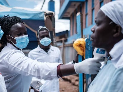 Tres trabajadores voluntarios toman la temperatura a una habitante del barrio de chabolas de Kibera, en Kenia.