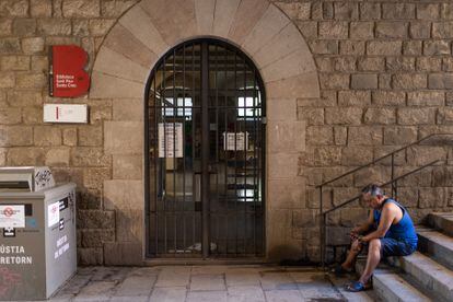 Un ciudadano descansa mientras toma el aire en el acceso exterior de la biblioteca Sant Pau-Santa Creu habilitada como refugio climático pero cerrada esta primera quincena de agosto.