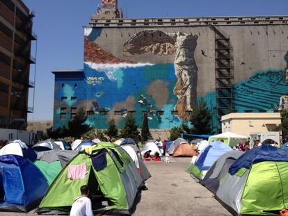 El campamento de refugiados del Pireo con un grafiti de la Victoria de Samotracia al fondo.