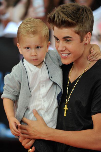 Justin Bieber llegó acompañado de su hermano. Bueno, más bien llegó con su hermanito en brazos.
