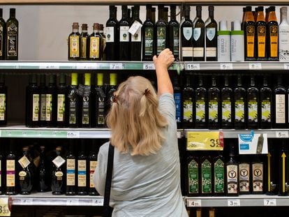 Una clienta de un supermercado español elige una botella de aceite de oliva.