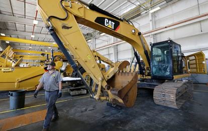 Un empleado de una empresa de maquinaria industrial pasa junto a una excavadora en Flowood, Mississippi, septiembre de 2019.