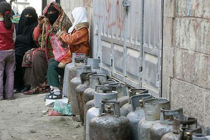 Mujeres yemeníes esperan sentadas sumistro de gas para cocinar en Saná.