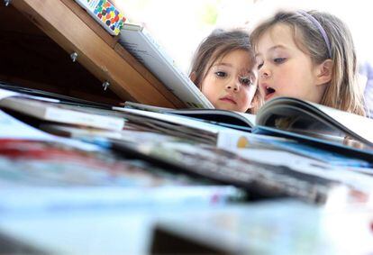 Ana y Lucía, de 4 y 6 años, miran libros en una caseta de la Feria del Libro de Madrid.