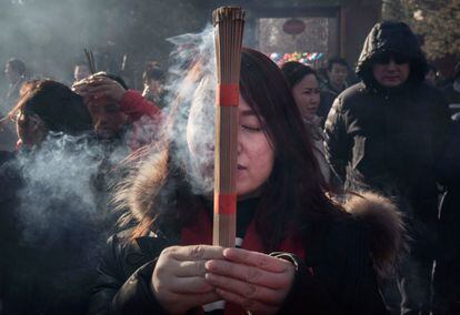 Una mujer reza mientras quema incienso en un templo en Pekín durante la celebración del Año Nuevo.