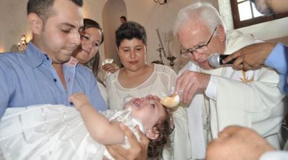 Natalia durante el bautizo con su padrino, las dos madres y el obispo Ra&uacute;l Vera.