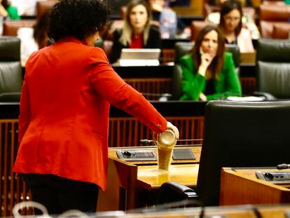 La diputada Maribel Mora derrama arena en el escaño del presidente de la Junta, Juan Manuel Moreno, en el pleno del Parlamento el 12 de abril.