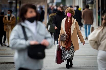 Varias personas con mascarilla pasean por una calle de Madrid.