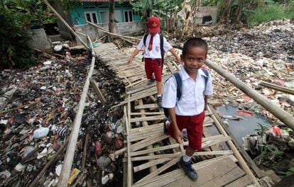 Dos niños cruzan un puente de bambú sobre un río de basura en Bogor, Indonesia. 