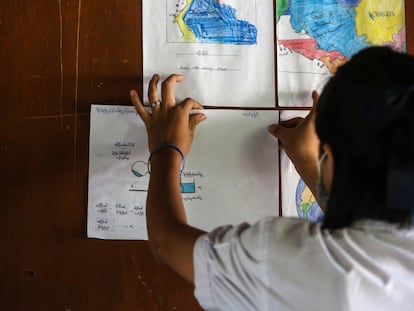 Aye Aye Than pega una tarea de ciencias en la pared de su clase en un Centro de Aprendizaje para Migrantes en Mae Sot, Tailandia, donde vive refugiada tras el golpe de estado militar en su país, Myanmar.