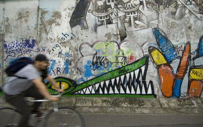 Un ciclista ante uno de los murales de la East Side Gallery, en Berl&iacute;n. 