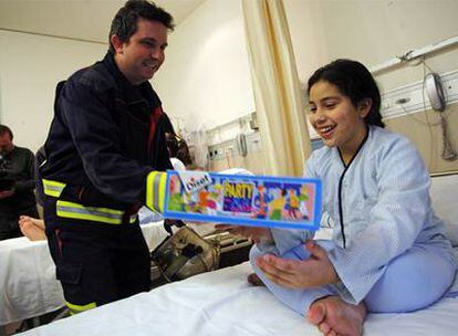 Kaltuma, de 11 años, recibe la visita de los bomberos en el hospital Gregorio Marañón.