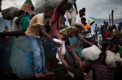 Hombres haitianos descargan un pequeño barco que ha llegado al puerto de Port-au-Prince procedente de zonas rurales de Haití, mientras otras descargan mientras otros descargan mercancías. 28 de septiembre de 2010.