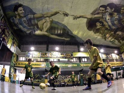 Niños juegan fútbol sala en Sportivo Barracas, un club de barrio de Buenos Aires. En el techo, la versión del artista local Santiago Barbeito de 'La Creación de Adán', con Messi y Maradona, entre otros.