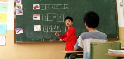 Un nen asiàtic aprèn català a l'escola.