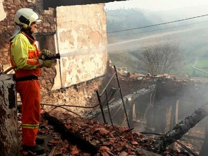 Un bombero trabaja este lunes en la zona de Sobrevega, en Grado (Asturias), donde el fuego afectó a una casa deshabitada.