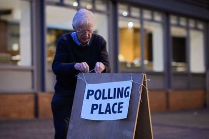Un hombre cuelga el cartel en un colegio electoral antes de que lleguen los votantes.