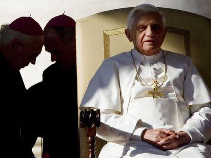 El Papa preside una audiencia en San Pedro mientras dos obispos conversan a su espalda.