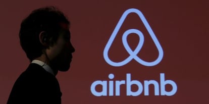 Un hombre pasea junto a un logotipo de Airbnb.