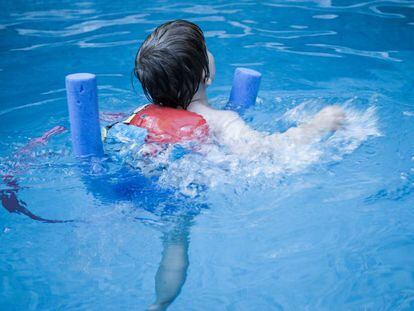 Un niño nada en una piscina. 