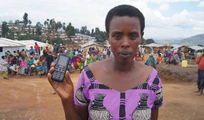 Jeantier Uwimana, refugiada de 39 a&ntilde;os y madre de 9 hijos, recibe el dinero asociado a un tel&eacute;fono m&oacute;vil. Al fondo, el campo de Kigeme.