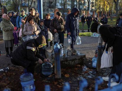 Vecinos de Kiev llenan garrafas con agua potable, tras una serie de bombardeos a las infraestructuras de la capital que les han dejado sin suministro, el pasado 30 de noviembre.