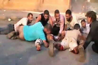 Varias personas se ponen a cubierto del tiroteo atribuido al Ejército en Hama, en una imagen captada de un vídeo   colgado en YouTube.