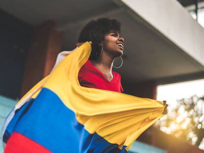 Una mujer sostiene una bandera de Colombia. 
