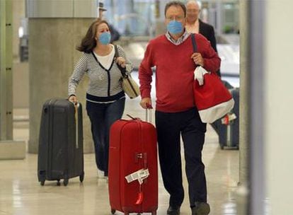 Pasajeros procedentes de México llegan al aeropuerto de Madrid Barajas con mascarillas protectoras.