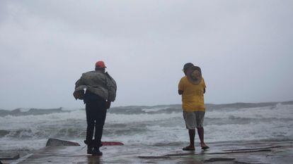 Las autoridades del país insular han reportado que un hombre de 72 años murió en el municipio de Nagua, luego de que un árbol le cayera encima. En la imagen, dos hombres observan el mar durante el paso del ciclón, en Nagua. 