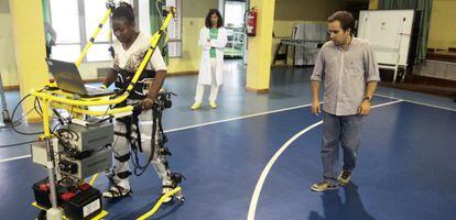 Eloy Urendes, del CSIC, da indicaciones a una paciente parapl&eacute;jica que utiliza un prototipo de exoesqueleto.