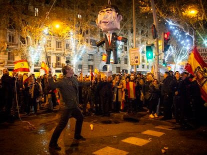 Un hombre se dispone a golpear una piñata que representa a Pedro Sánchez, cerca de la sede del PSOE en Madrid, esta Nochevieja.