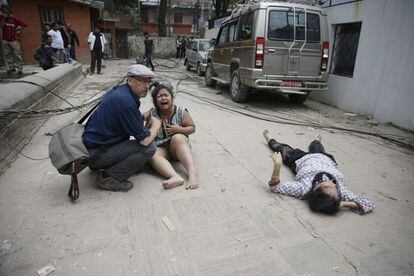 Un turista atiende a dos personas heridas tras el terremoto en Katmandú.