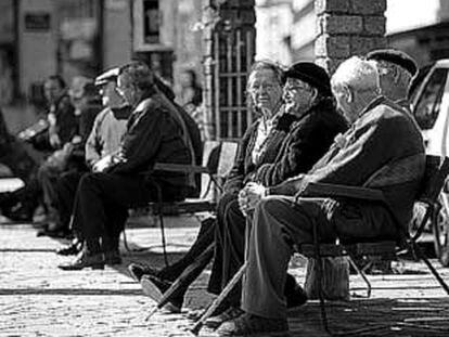 Varios ancianos toman el sol en los bancos de la plaza del pueblo de Ponteareas (Pontevedra).