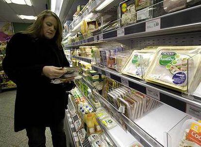 Una consumidora lee el etiquetado de bandejas de carne de cerdo en un supermercado de Belfast.