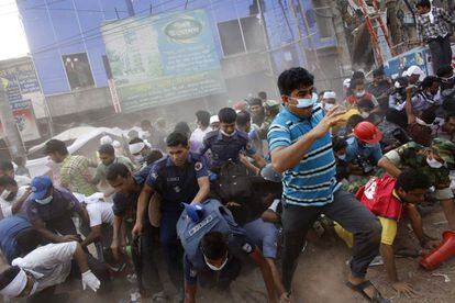 Equipos de rescate salen corriendo tras desprenderse parte del edificio durante las labores de rescate de víctimas en la ciudad de Dacca (Bangladesh).