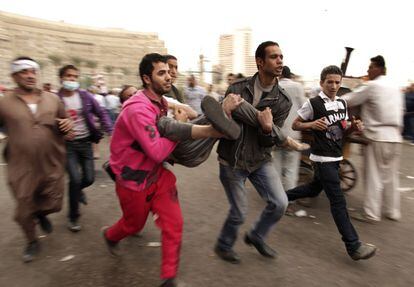Manifestantes evacuan a un compañero herido durante los choques entre seguidores y detractores del presidente Morsi en la plaza de la Liberación de El Cairo.