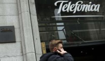 Un hombre habla por su móvil junto a la sede de Telefónica en Gran Vía.