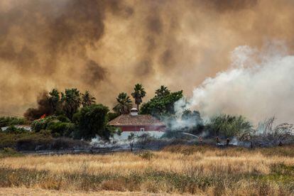 Los bomberos combaten las llamas cerca de una casa amenazada por un incendio en el área de Ludo, Faro, Algarve, sur de Portugal.