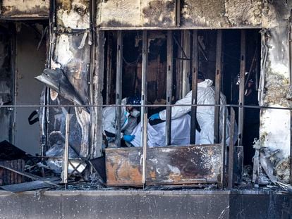 Bomberos y policía nacional trabajan en el edificio que fue devastado el jueves por las llamas.