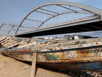 Un chico permanece sentado en un cayuco de pescadores junto a un puente a medio construir en Dakar, Senegal, el 13 de julio de 2020.
