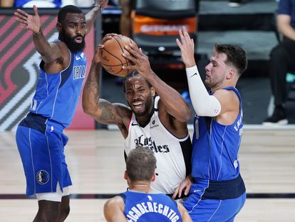 Luka Doncic intenta frenar a Kawhi Leonard.