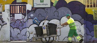 Un empleado del servicio de limpieza pasa frente al instituto afectado por una plaga en Jerez. 