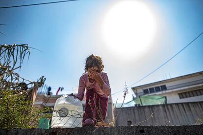 Una niña coge un bidón de agua en el campo de refugiados improvisado de Mitilene. 