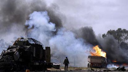 Un rebelde observa varios vehículos quemados pertenecientes a las fuerzas leales al líder libio