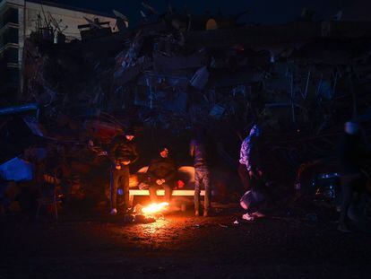 Un grupo de ciudadanos se calienta en una hoguera entre los escombros de los edificios derrumbados en la ciudad turca de Kahramanmaras este martes.