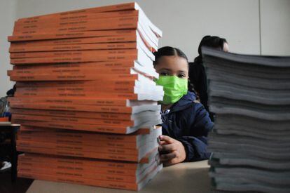 En agosto de 2022, una niña se asoma detrás de una torre de libros de texto de la SEP, en una primaria de la Ciudad de México.