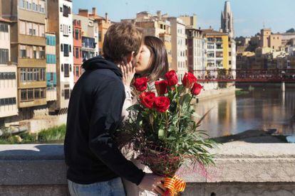 Una parella es fa un petó en un pont de Girona.