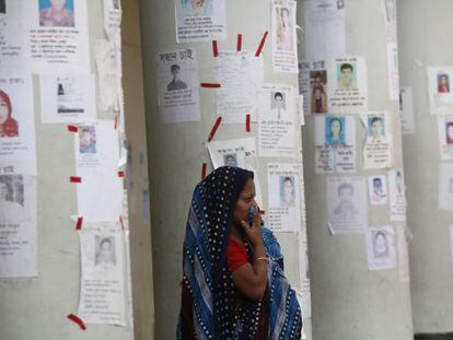Una mujer espera noticias rodeada de carteles de desaparecidos.